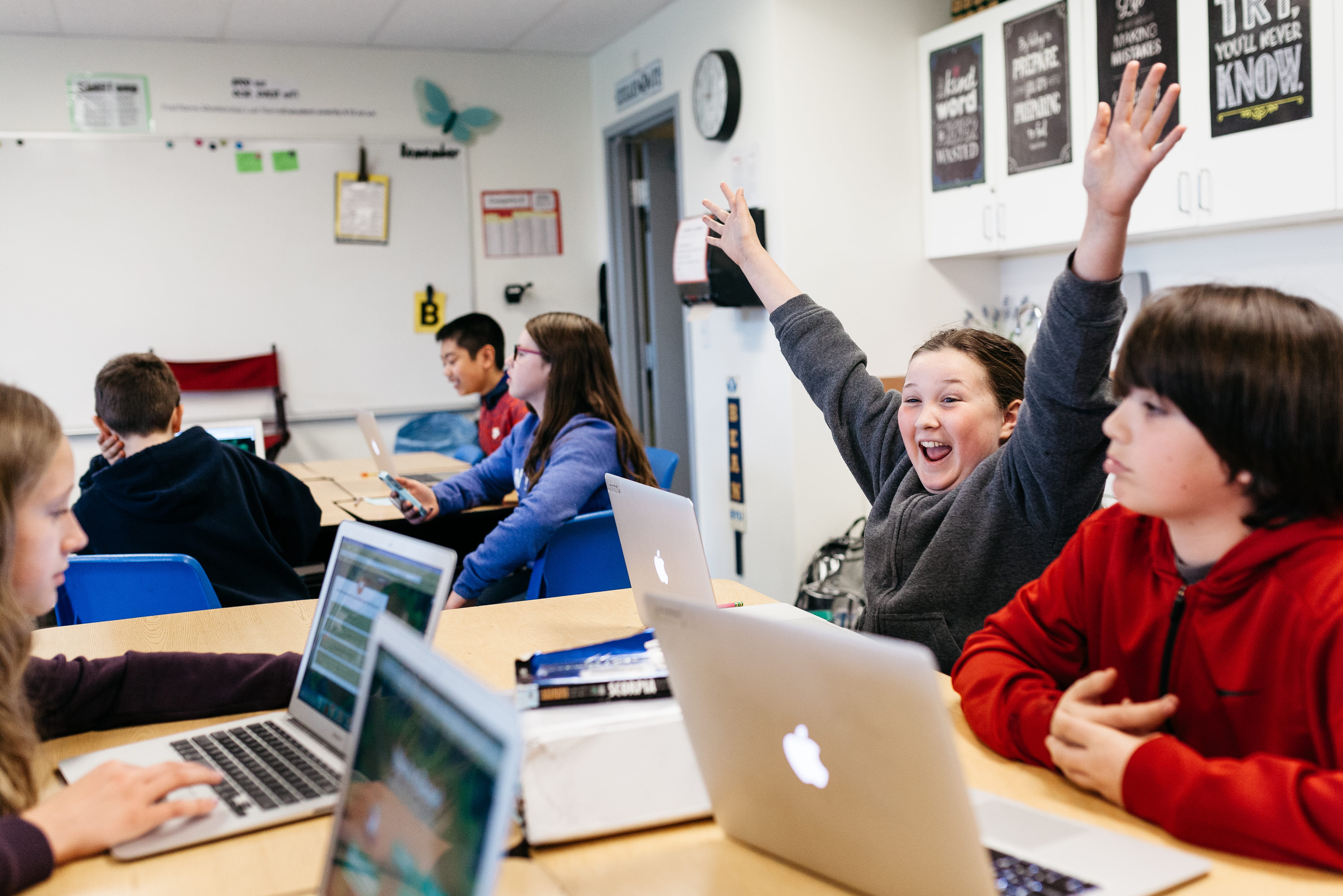 A student celebrating while working collaboratively with two other students